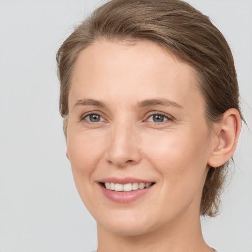 Joyful white young-adult female with medium  brown hair and grey eyes