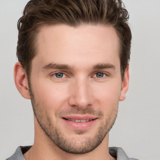 Joyful white young-adult male with short  brown hair and grey eyes