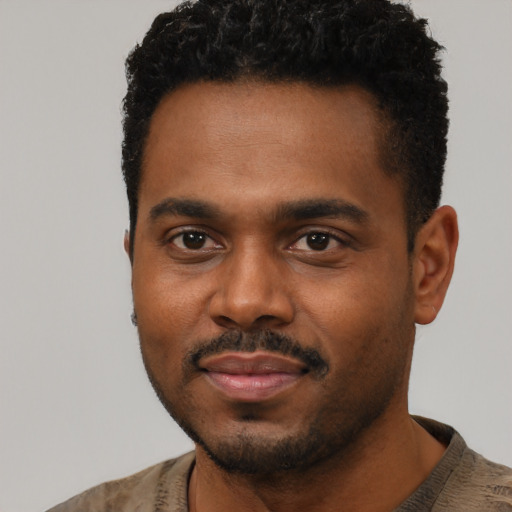 Joyful black young-adult male with short  black hair and brown eyes