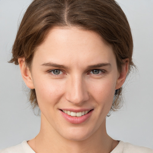 Joyful white young-adult female with medium  brown hair and grey eyes