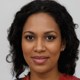 Joyful black adult female with long  brown hair and brown eyes