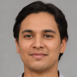 Joyful latino young-adult male with short  brown hair and brown eyes