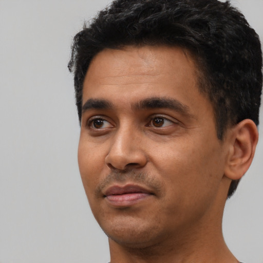 Joyful latino young-adult male with short  black hair and brown eyes