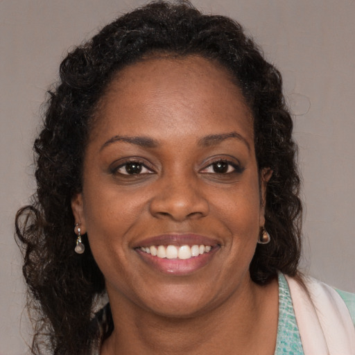 Joyful black young-adult female with long  brown hair and brown eyes