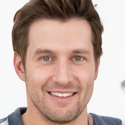 Joyful white young-adult male with short  brown hair and grey eyes