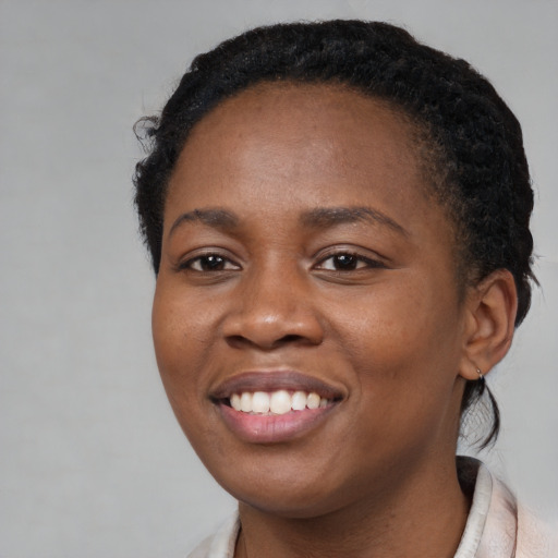 Joyful black young-adult female with short  black hair and brown eyes