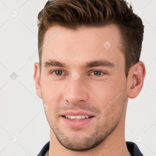 Joyful white young-adult male with short  brown hair and grey eyes