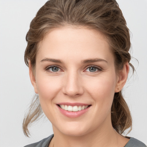 Joyful white young-adult female with medium  brown hair and grey eyes