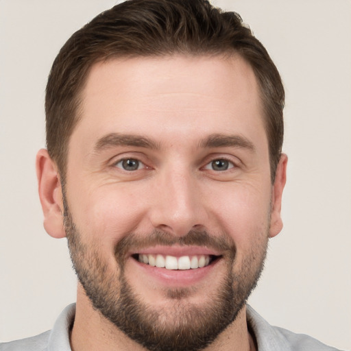 Joyful white young-adult male with short  brown hair and grey eyes