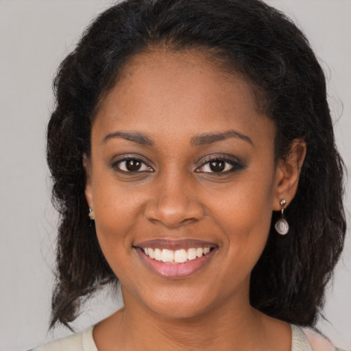 Joyful black young-adult female with long  brown hair and brown eyes