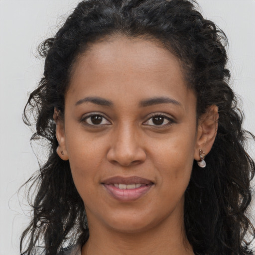 Joyful black young-adult female with long  brown hair and brown eyes