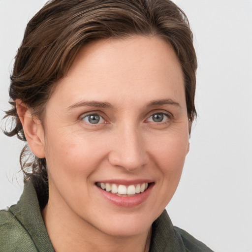 Joyful white young-adult female with medium  brown hair and grey eyes