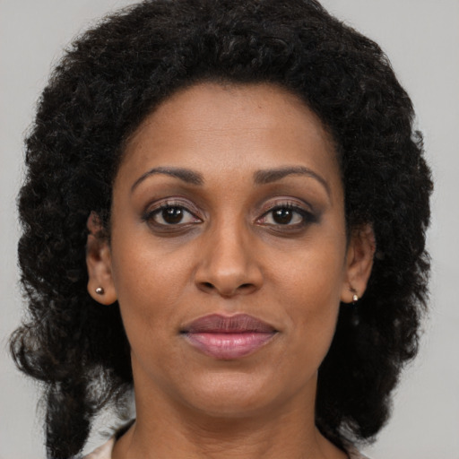 Joyful black adult female with long  brown hair and brown eyes