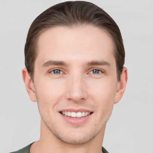 Joyful white young-adult male with short  brown hair and grey eyes