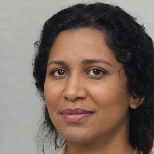 Joyful black adult female with long  black hair and brown eyes