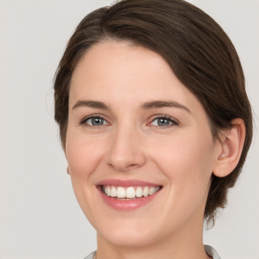 Joyful white young-adult female with medium  brown hair and grey eyes