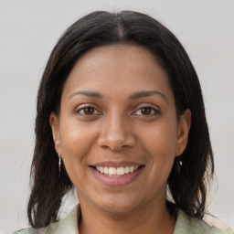 Joyful black young-adult female with long  brown hair and brown eyes