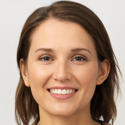 Joyful white young-adult female with medium  brown hair and grey eyes