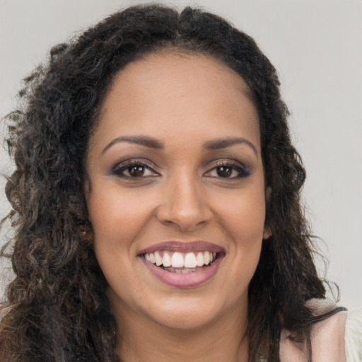 Joyful black young-adult female with long  brown hair and brown eyes