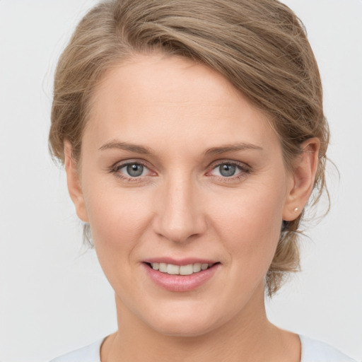 Joyful white young-adult female with medium  brown hair and grey eyes