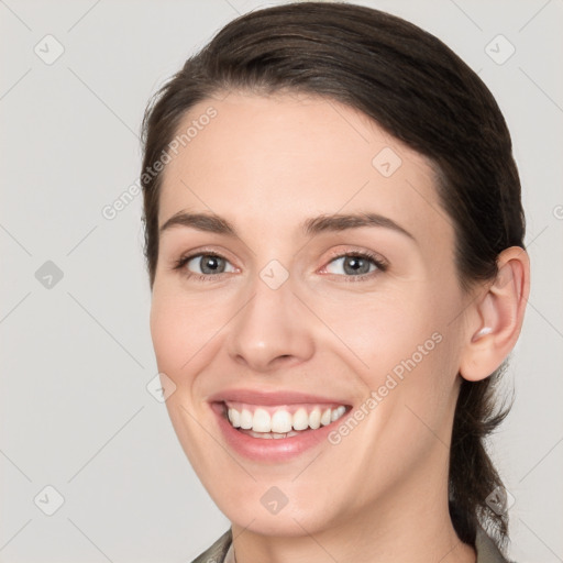 Joyful white young-adult female with medium  brown hair and grey eyes