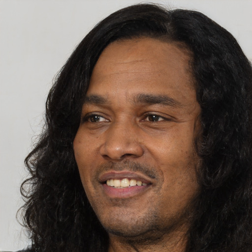 Joyful black adult male with long  black hair and brown eyes