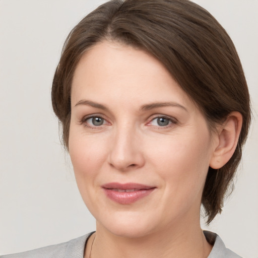 Joyful white young-adult female with medium  brown hair and grey eyes