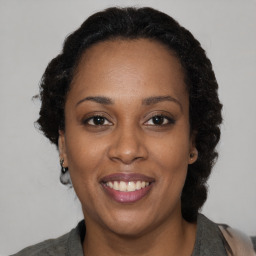 Joyful black adult female with medium  brown hair and brown eyes