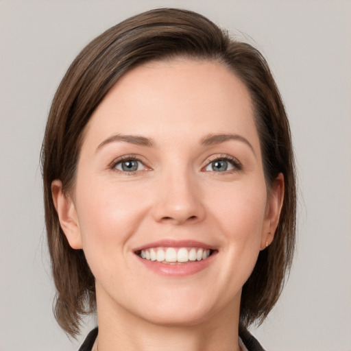 Joyful white young-adult female with medium  brown hair and grey eyes