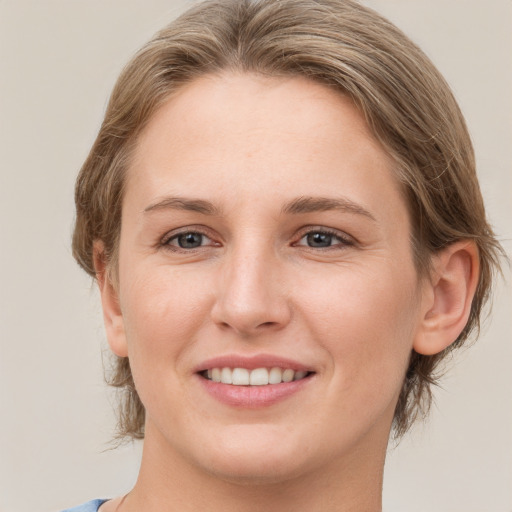 Joyful white young-adult female with medium  brown hair and grey eyes