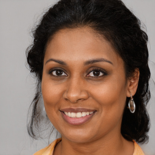 Joyful black young-adult female with long  brown hair and brown eyes
