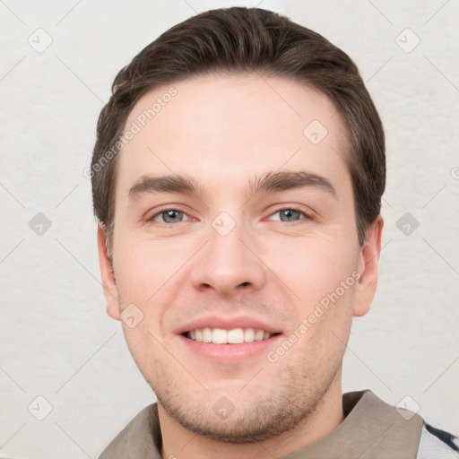 Joyful white young-adult male with short  brown hair and grey eyes