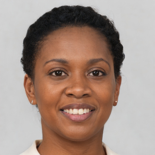 Joyful black young-adult female with short  brown hair and brown eyes