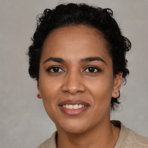 Joyful black young-adult female with short  black hair and brown eyes