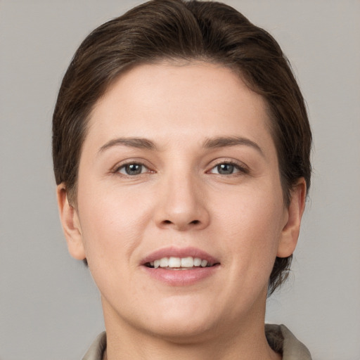 Joyful white young-adult female with short  brown hair and grey eyes