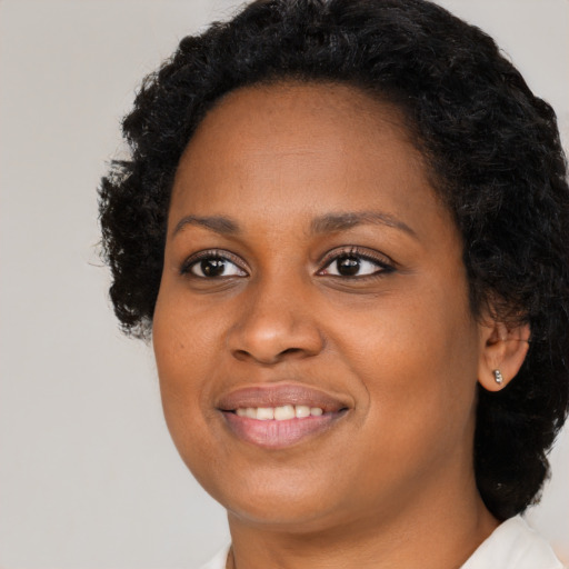 Joyful black young-adult female with long  black hair and brown eyes