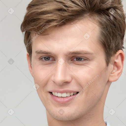 Joyful white young-adult male with short  brown hair and grey eyes