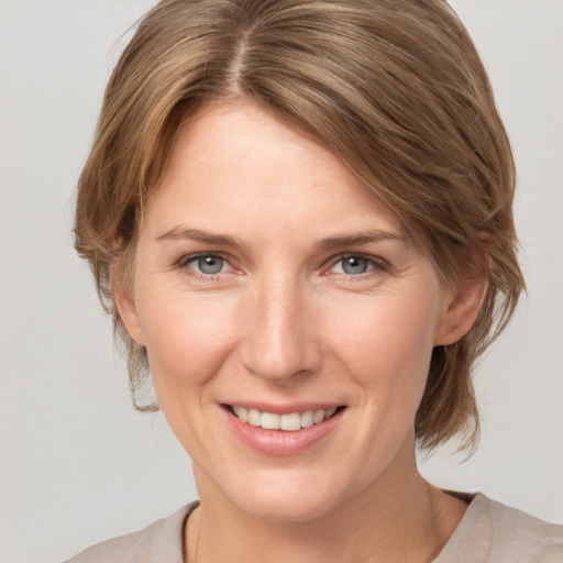 Joyful white young-adult female with medium  brown hair and grey eyes