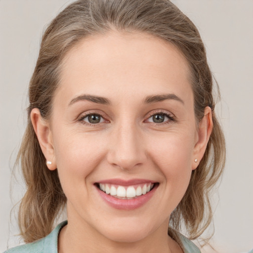 Joyful white young-adult female with medium  brown hair and grey eyes