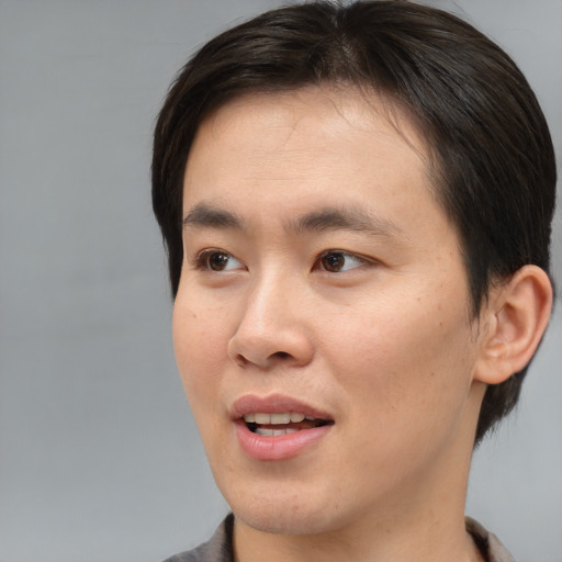 Joyful asian young-adult male with short  brown hair and brown eyes