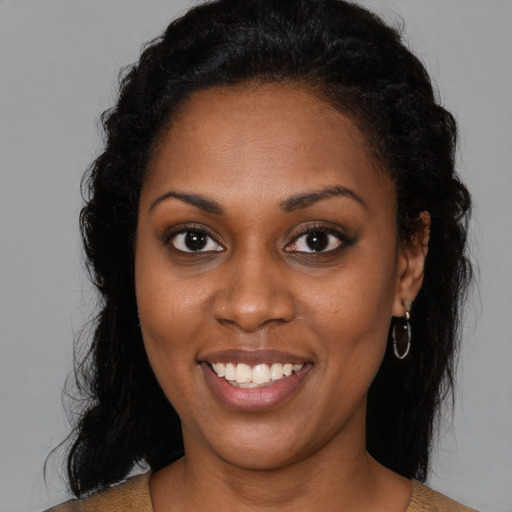 Joyful black young-adult female with long  brown hair and brown eyes