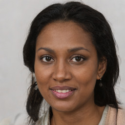 Joyful black young-adult female with long  brown hair and brown eyes