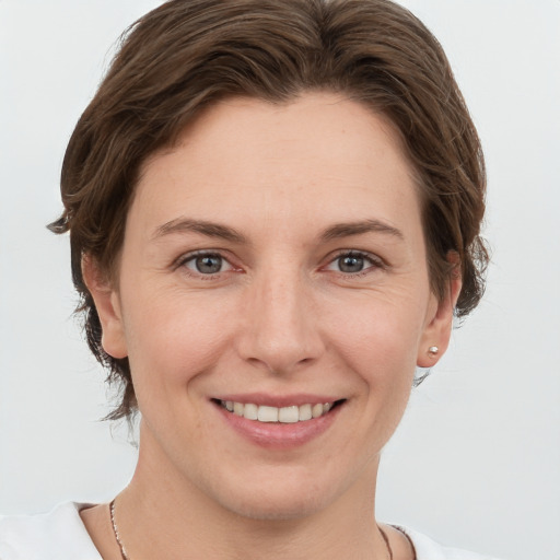 Joyful white young-adult female with short  brown hair and grey eyes