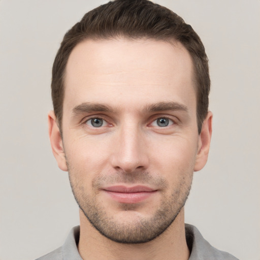 Joyful white young-adult male with short  brown hair and grey eyes