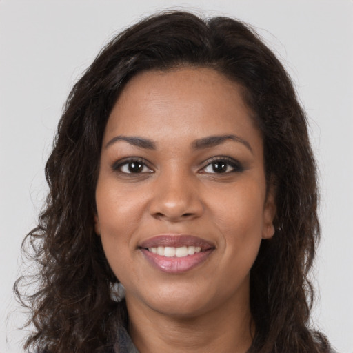 Joyful black young-adult female with long  brown hair and brown eyes
