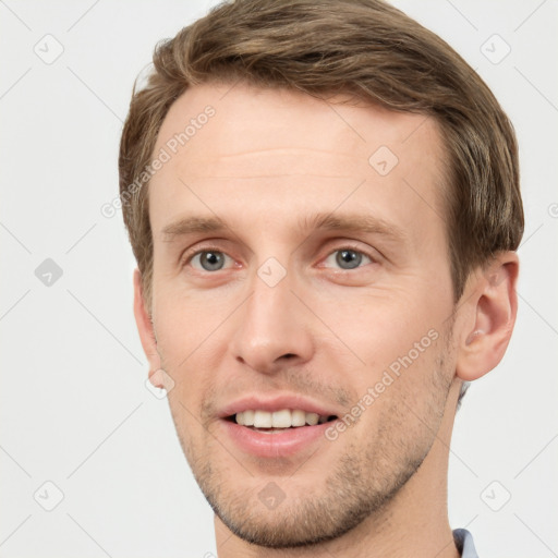 Joyful white young-adult male with short  brown hair and grey eyes