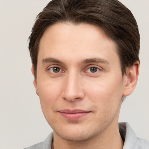 Joyful white young-adult male with short  brown hair and grey eyes