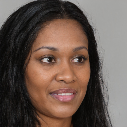 Joyful black young-adult female with long  brown hair and brown eyes
