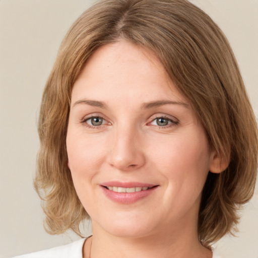 Joyful white young-adult female with medium  brown hair and green eyes