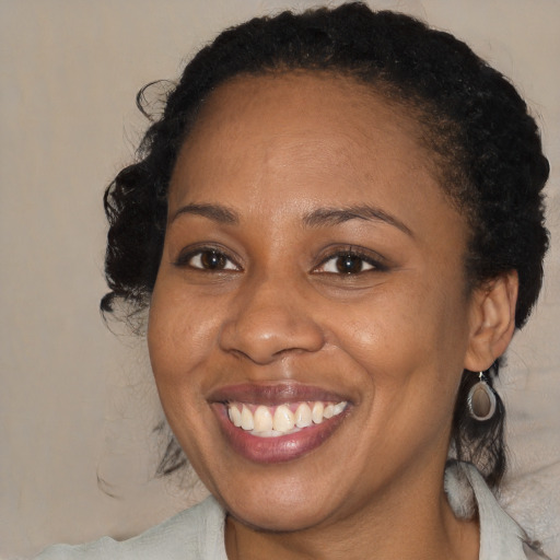 Joyful black young-adult female with medium  brown hair and brown eyes